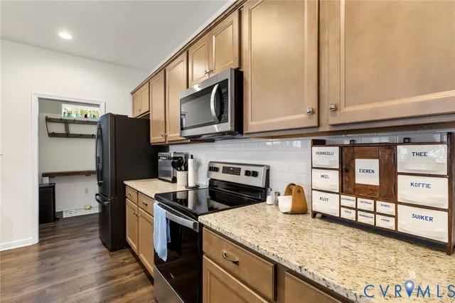 a kitchen with a stove a sink dishwasher a dining table and chairs with wooden floor