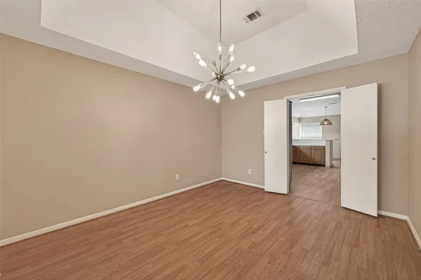 a view of a kitchen with a refrigerator a stove top oven hallway wooden floor and a living room
