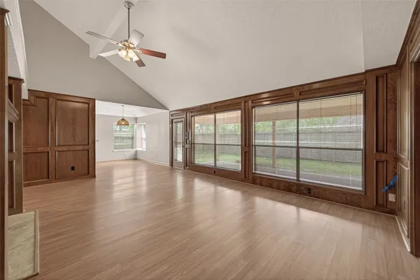 an empty room with wooden floor and windows