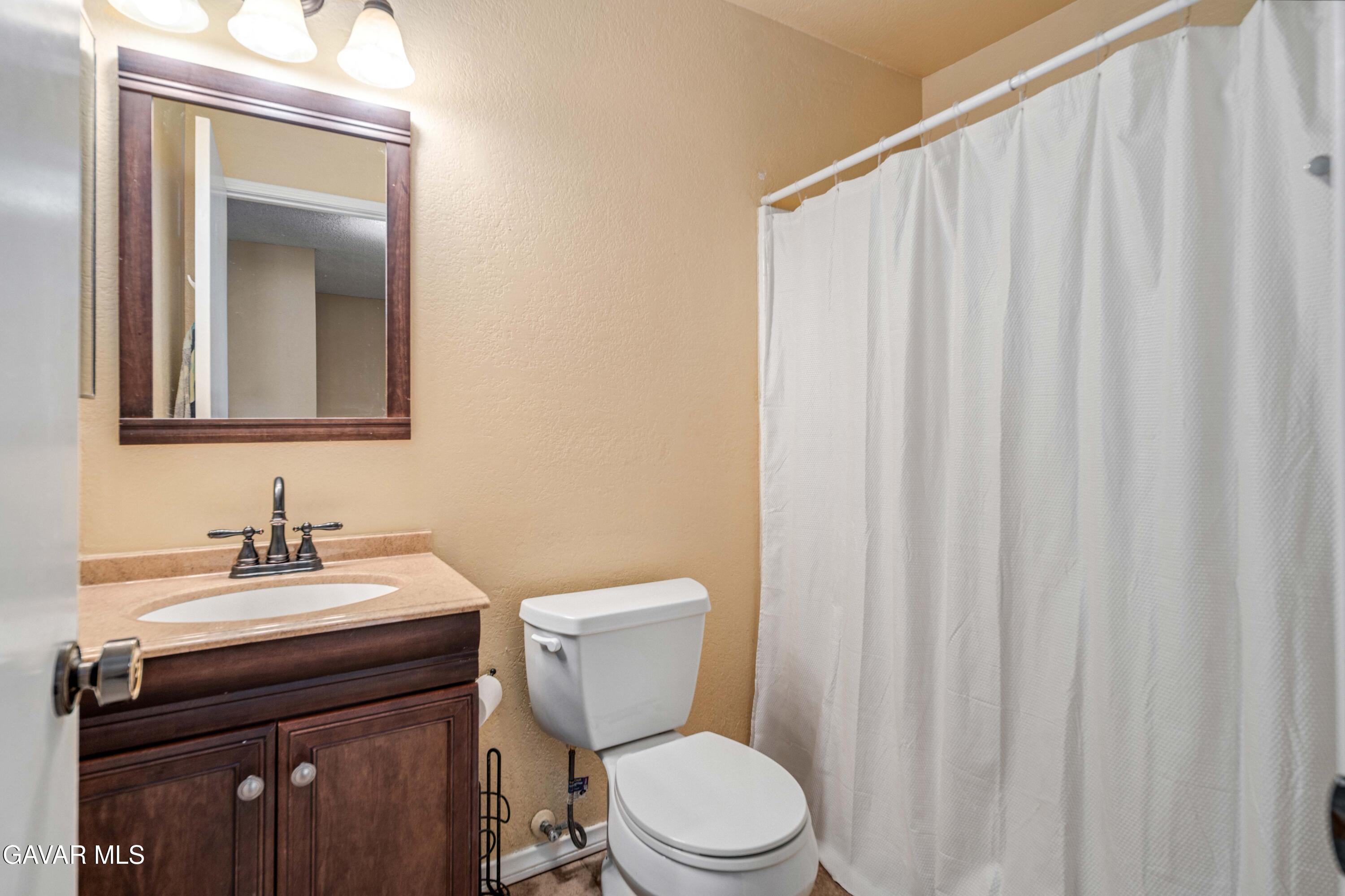 1605 Bluebell Street Lancaster, CA 93535 - Photo 31 of 40 a bathroom with a sink a toilet a mirror and shower curtain