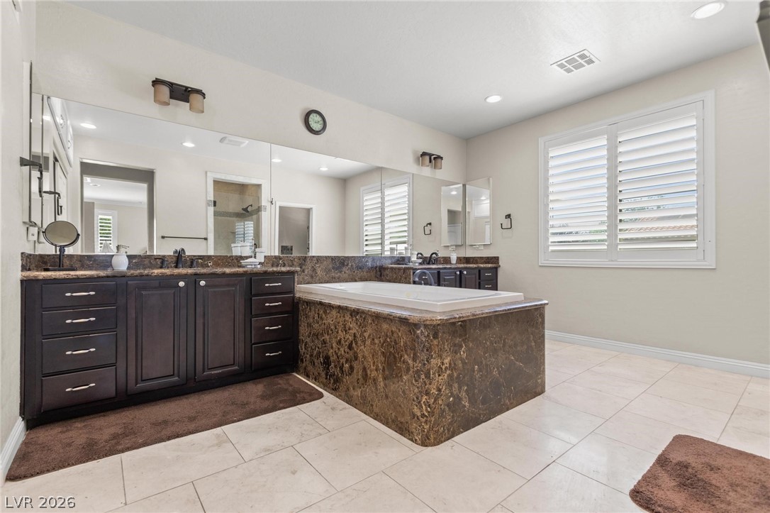 8431 Durango Ranch Court Las Vegas, NV 89113 - Photo 29 of 49 This spacious bathroom offers a relaxing soaking tub and dual vanities, perfect for daily routines.