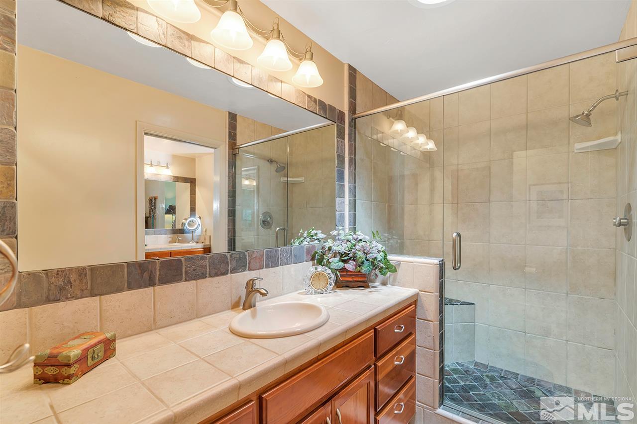 253 Cheyenne Circle Zephyr Cove, NV 89448 - Photo 12 of 25 a bathroom with a granite countertop sink a mirror and a shower