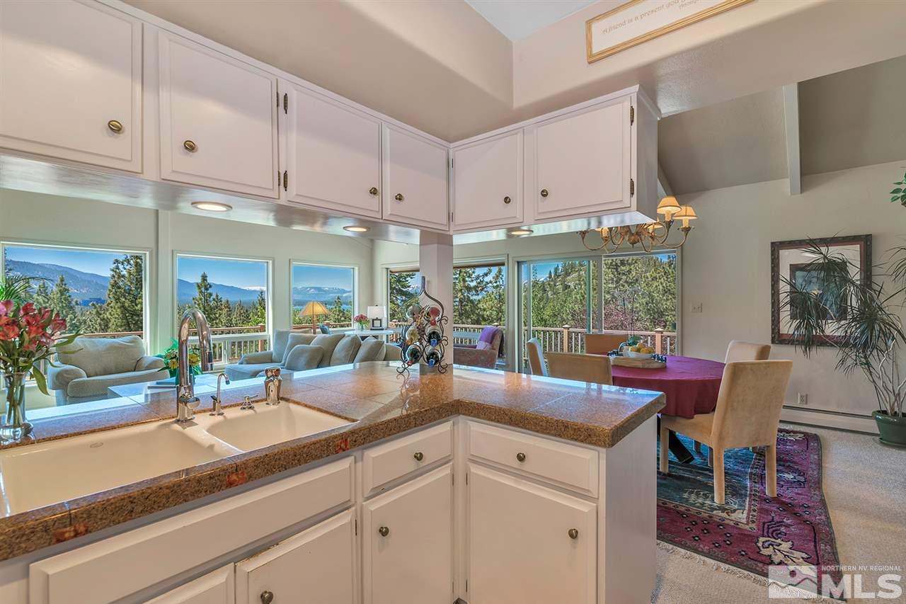 253 Cheyenne Circle Zephyr Cove, NV 89448 - Photo 7 of 25 a kitchen with kitchen island granite countertop a sink and white cabinets next to a window