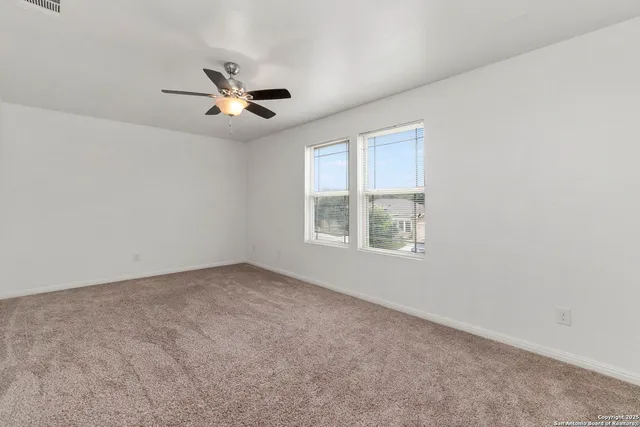 an empty room with windows and fan