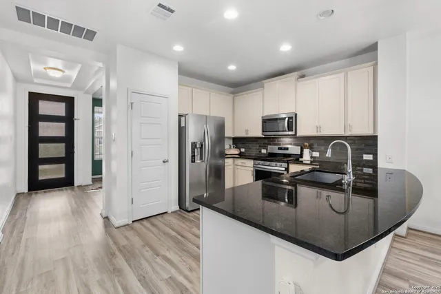 a kitchen with stainless steel appliances granite countertop a refrigerator a stove top oven a sink and dishwasher