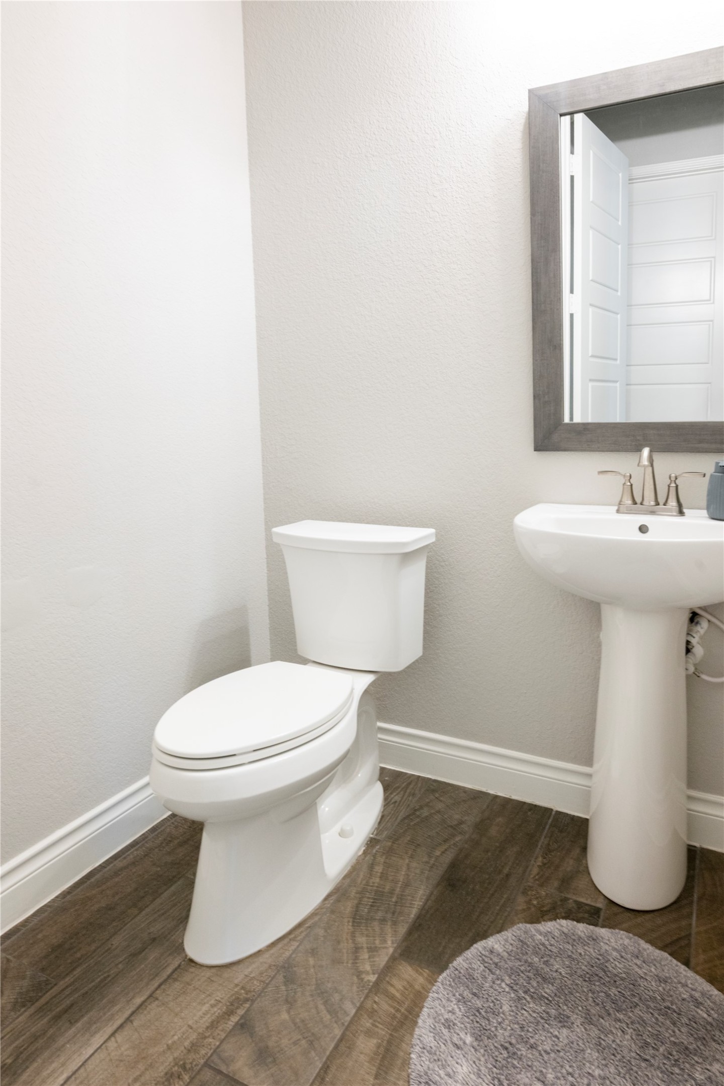140 Catani Loop Georgetown, TX 78628 - Photo 27 of 36 A well-lit half bathroom featuring wood-look tile flooring and a pedestal sink.