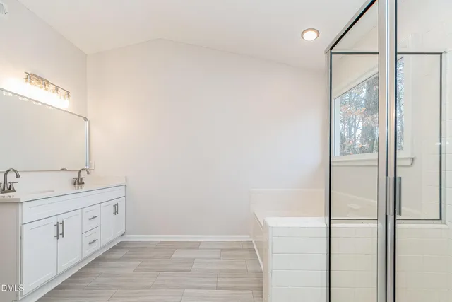a spacious bathroom with a double vanity sink a mirror and shower