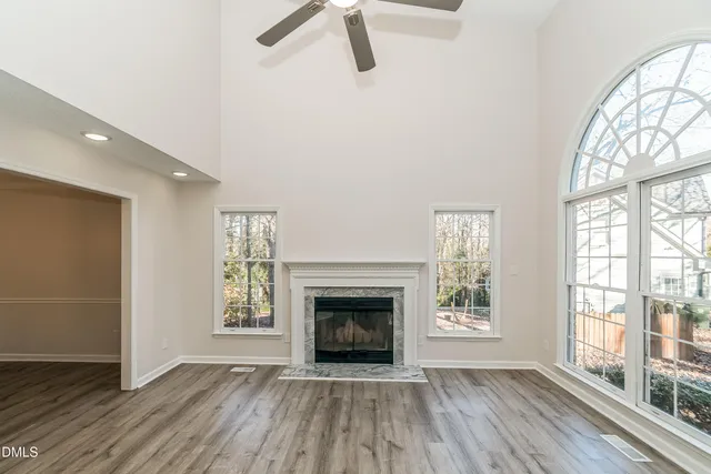 an empty room with wooden floor fireplace and windows