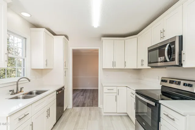 a kitchen with stainless steel appliances a sink stove and white cabinets