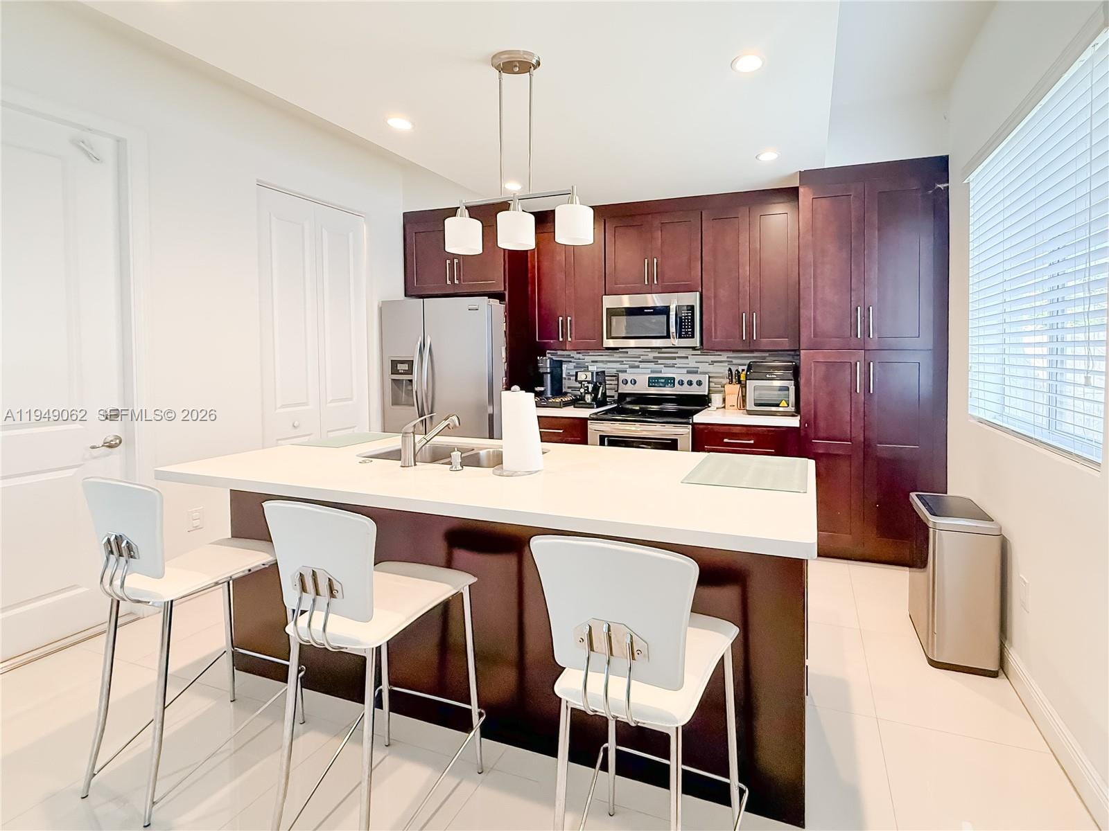 17931 Southwest 152nd Avenue Miami, FL 33187 - Photo 6 of 29 a kitchen with kitchen island granite countertop a sink and a refrigerator