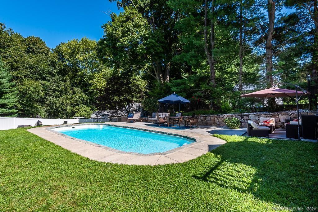 2 Valley Road Westport, CT 06880 - Photo 6 of 21 a view of a swimming pool with lawn chairs under an umbrella