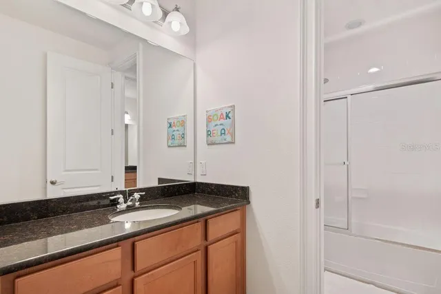a bathroom with a granite countertop sink and a mirror