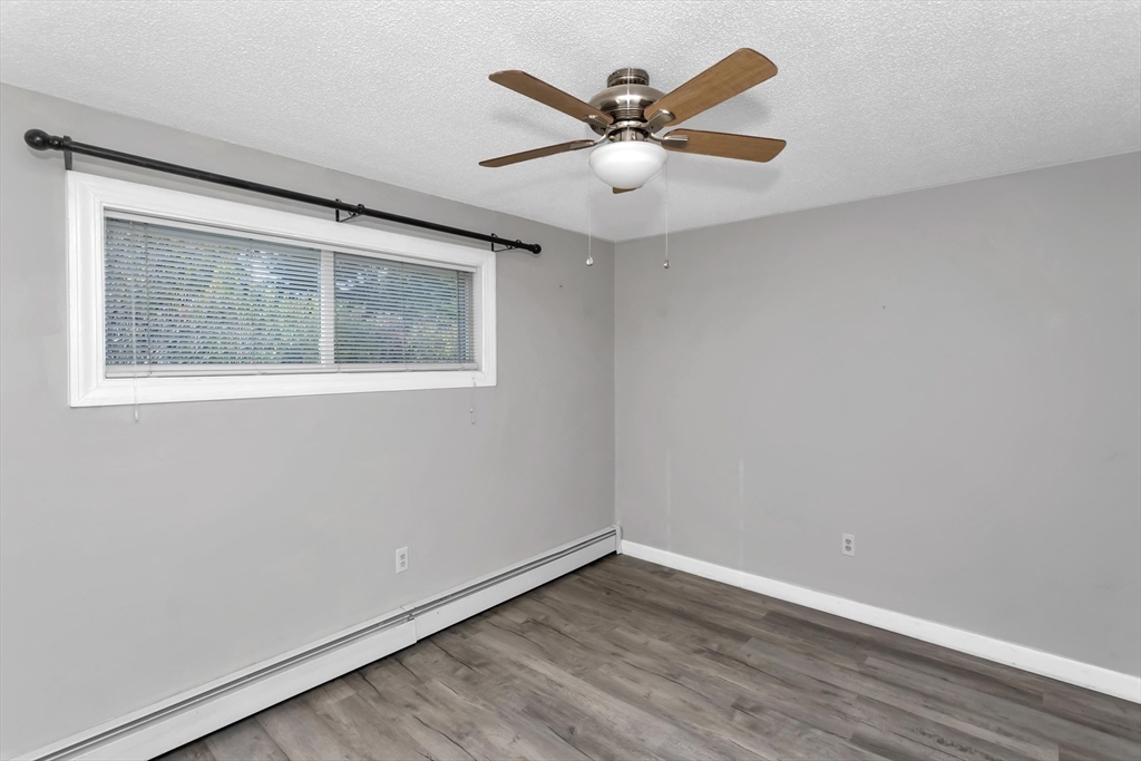 97 Collins Street, Unit 97 Chicopee, MA 01022 - Photo 11 of 21 an empty room with wooden floor and windows