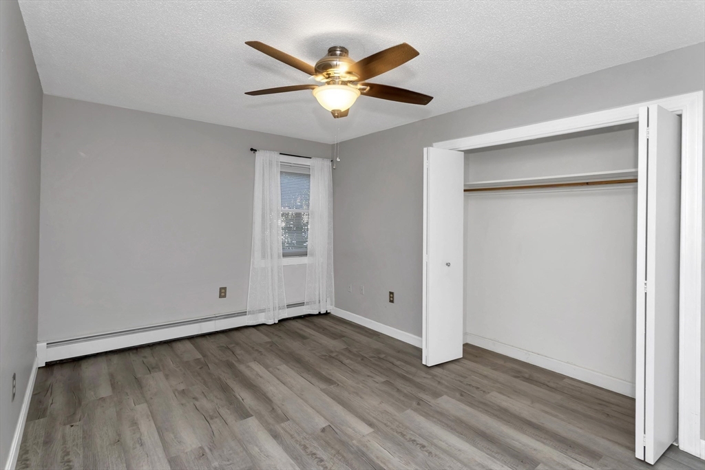 97 Collins Street, Unit 97 Chicopee, MA 01022 - Photo 15 of 21 an empty room with wooden floor and a ceiling fan