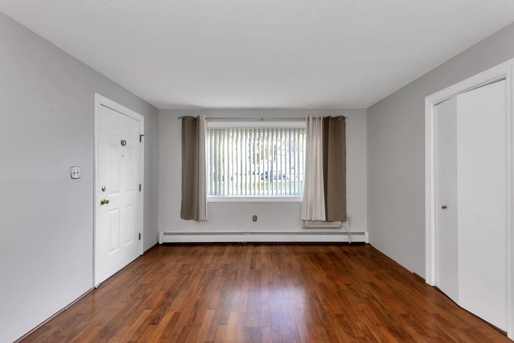 97 Collins Street, Unit 97 Chicopee, MA 01022 - Photo 10 of 21 an empty room with wooden floor and windows