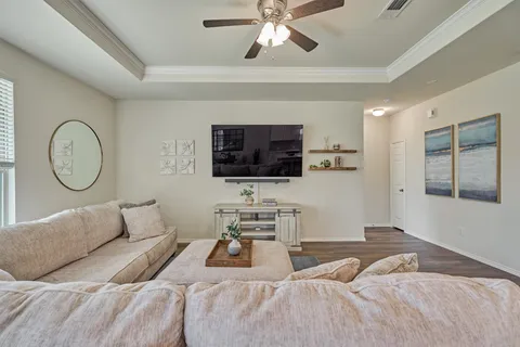 a living room with furniture kitchen view and a wooden floor
