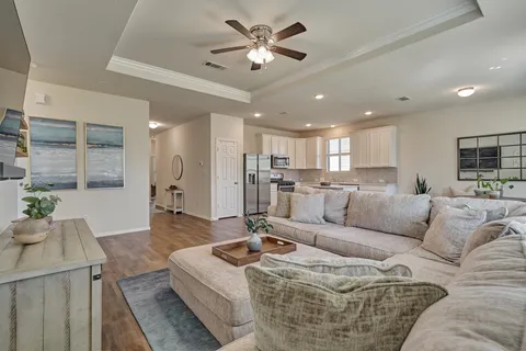 a living room with kitchen island granite countertop wooden floor and white cabinets