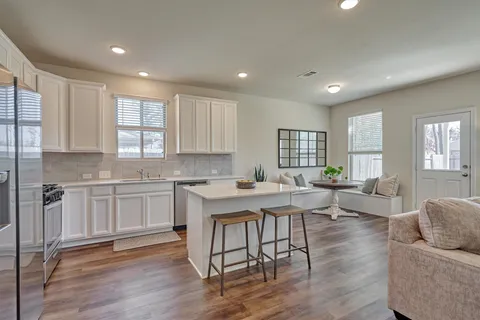 a kitchen with a sink a center island stainless steel appliances cabinets and a window