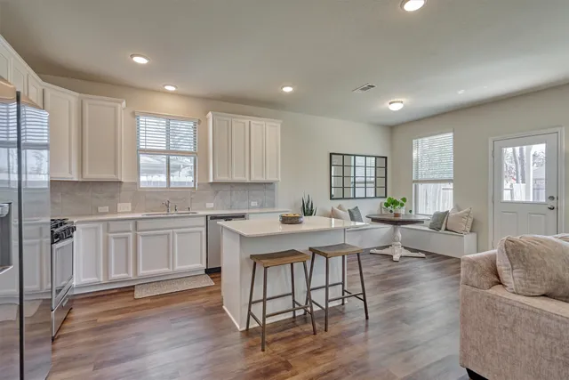 a kitchen with a sink a center island stainless steel appliances cabinets and a window