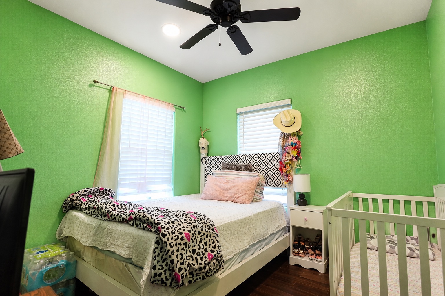 130 Los Arcos Road Elgin, TX 78621 - Photo 35 of 39 A vibrant bedroom features a clean-lined bed, rich wood flooring, and a window with blinds, creating a cheerful private retreat.