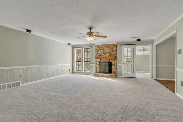 an empty room with fireplace and a ceiling fan