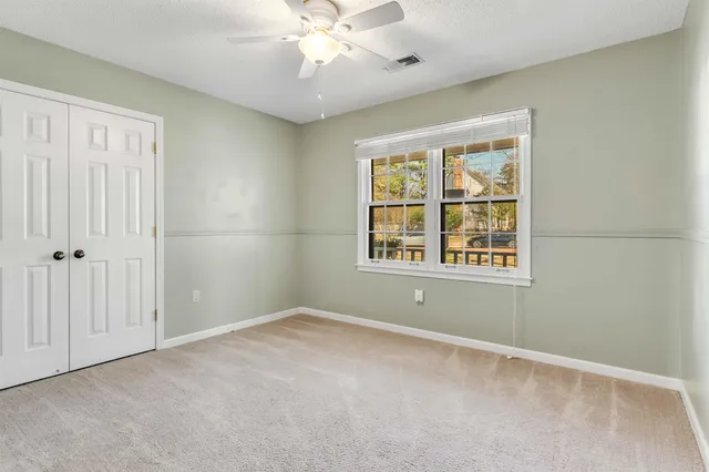 an empty room with windows and fan