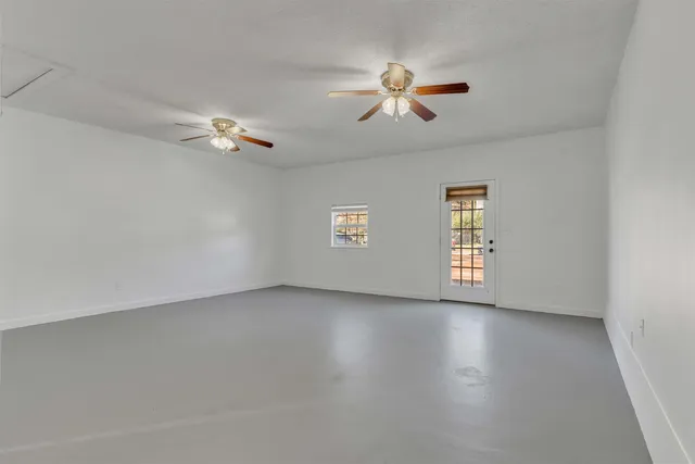 an empty room with a window and a ceiling fan