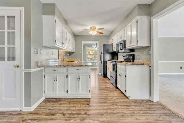 a kitchen with stainless steel appliances granite countertop a stove top oven a sink dishwasher and a refrigerator with wooden floor