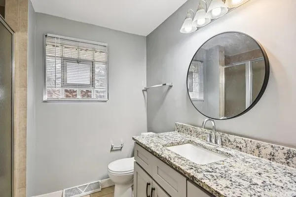a bathroom with a granite countertop toilet a sink and a mirror
