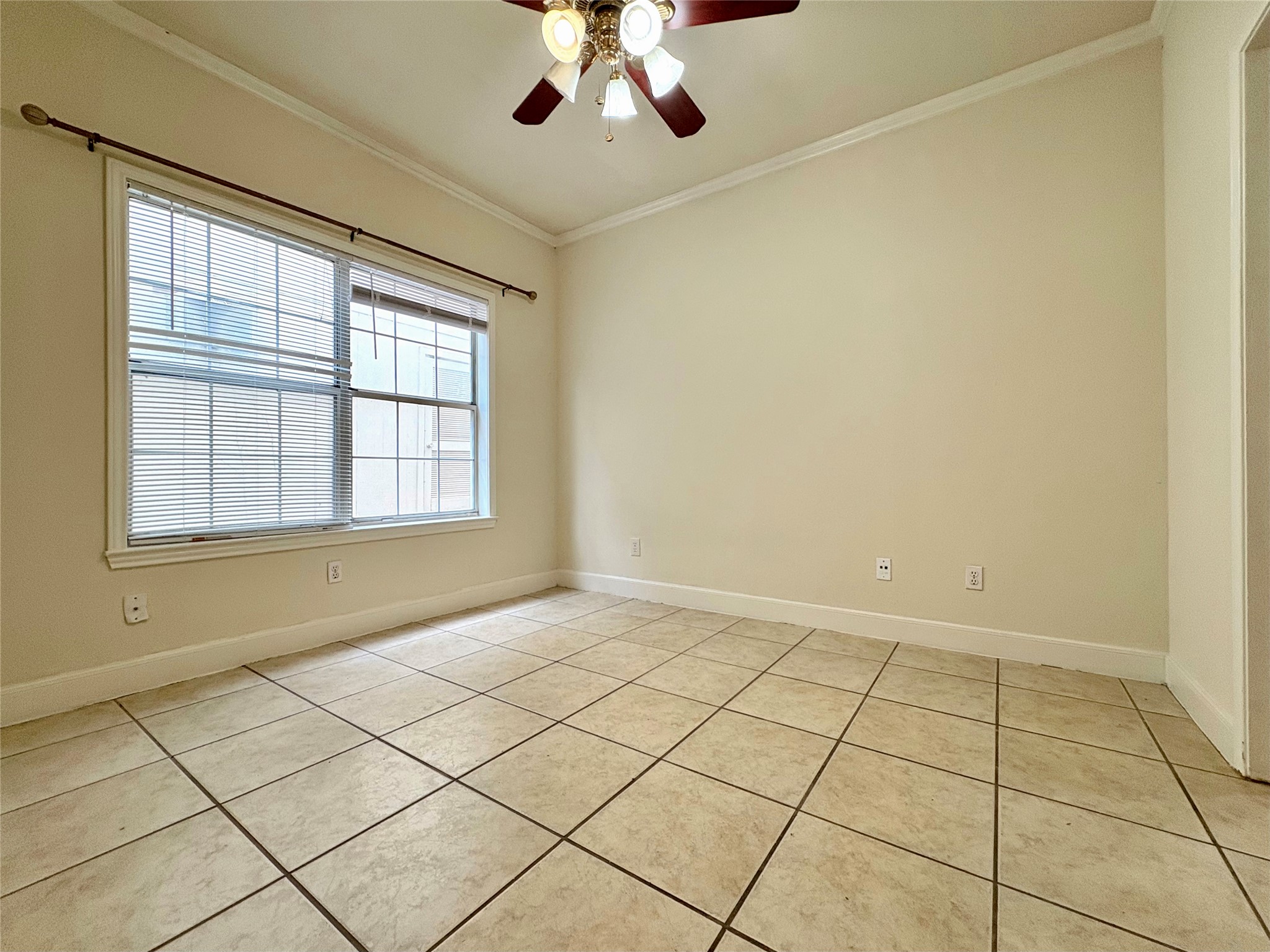 2100 San Gabriel Street, Unit 104 Austin, TX 78705 - Photo 7 of 8 Spare room featuring crown molding, light tile patterned floors, and a ceiling fan