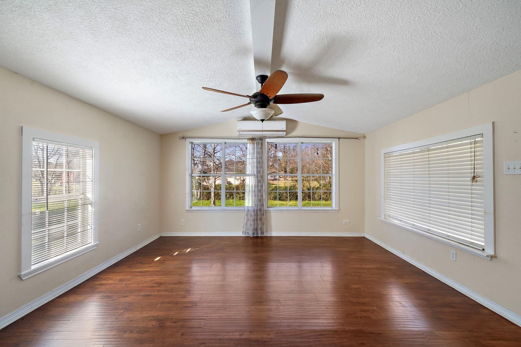 29115 Cherokee Lane Waller, TX 77484 - Photo 2 of 50 This spacious room features large windows that offer plenty of natural light, warm wood flooring, and a ceiling fan. Neutral walls provide a versatile backdrop for your decor. Ideal for a living or dining area.