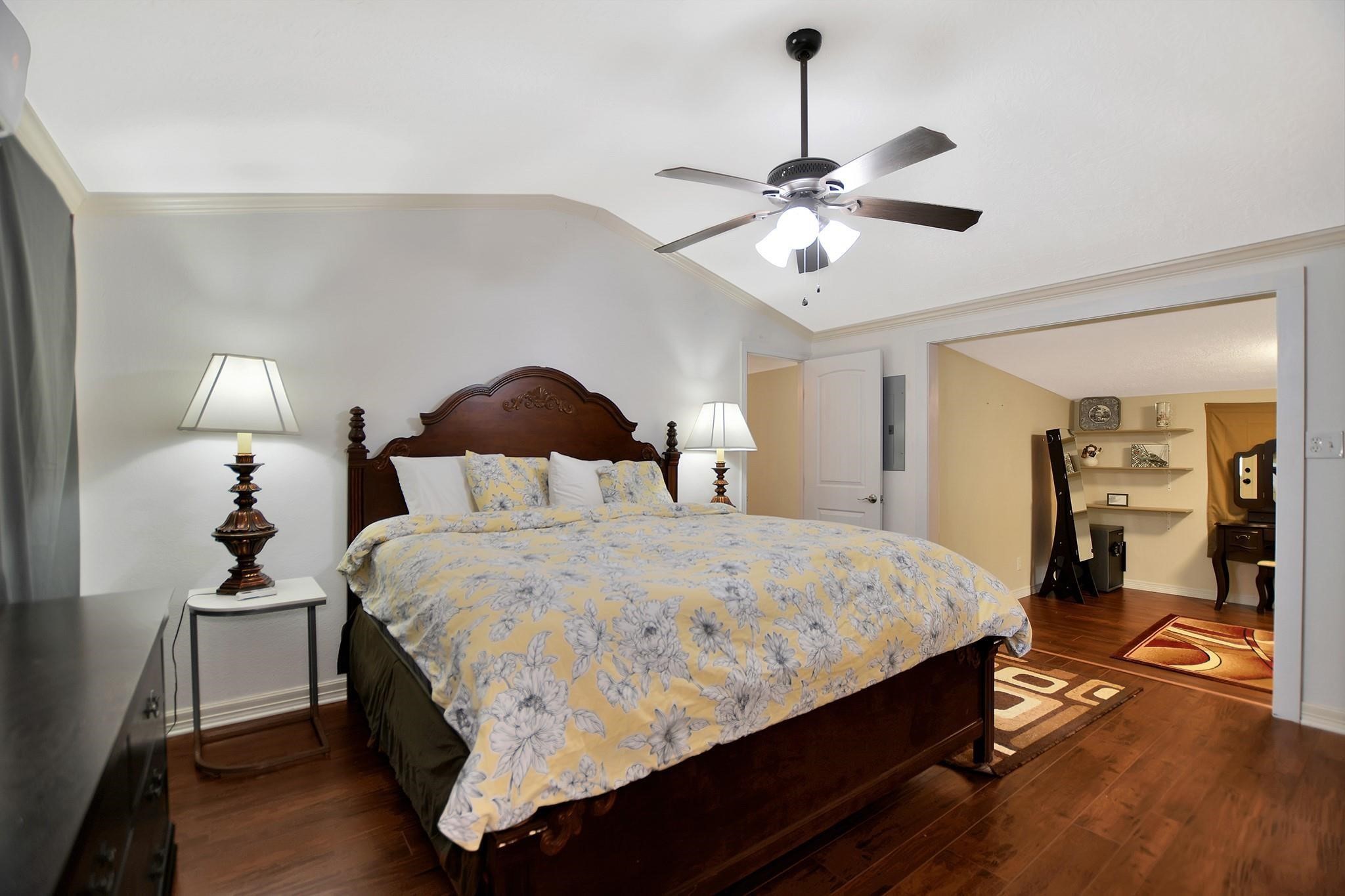 29115 Cherokee Lane Waller, TX 77484 - Photo 25 of 50 This spacious bedroom features elegant hardwood floors, a vaulted ceiling with a modern fan, and a cozy reading nook. It includes a large bed with a stylish headboard and complementary side lamps. The adjoining area offers additional space for a small office or seating area.