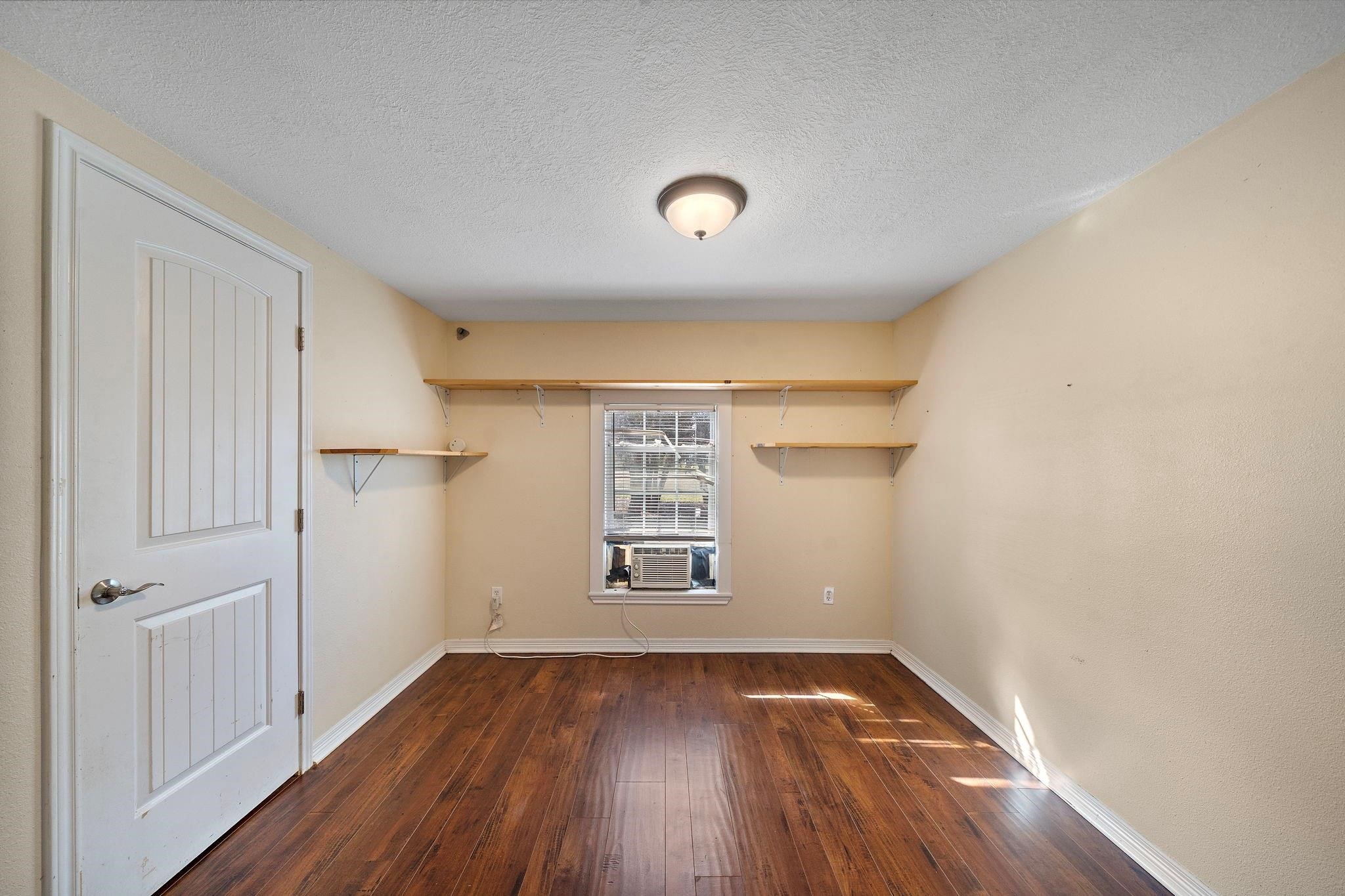29115 Cherokee Lane Waller, TX 77484 - Photo 26 of 50 This room features warm wooden flooring and neutral walls, with a window providing natural light. It includes built-in shelves and a ceiling light fixture, creating a cozy, functional space.
