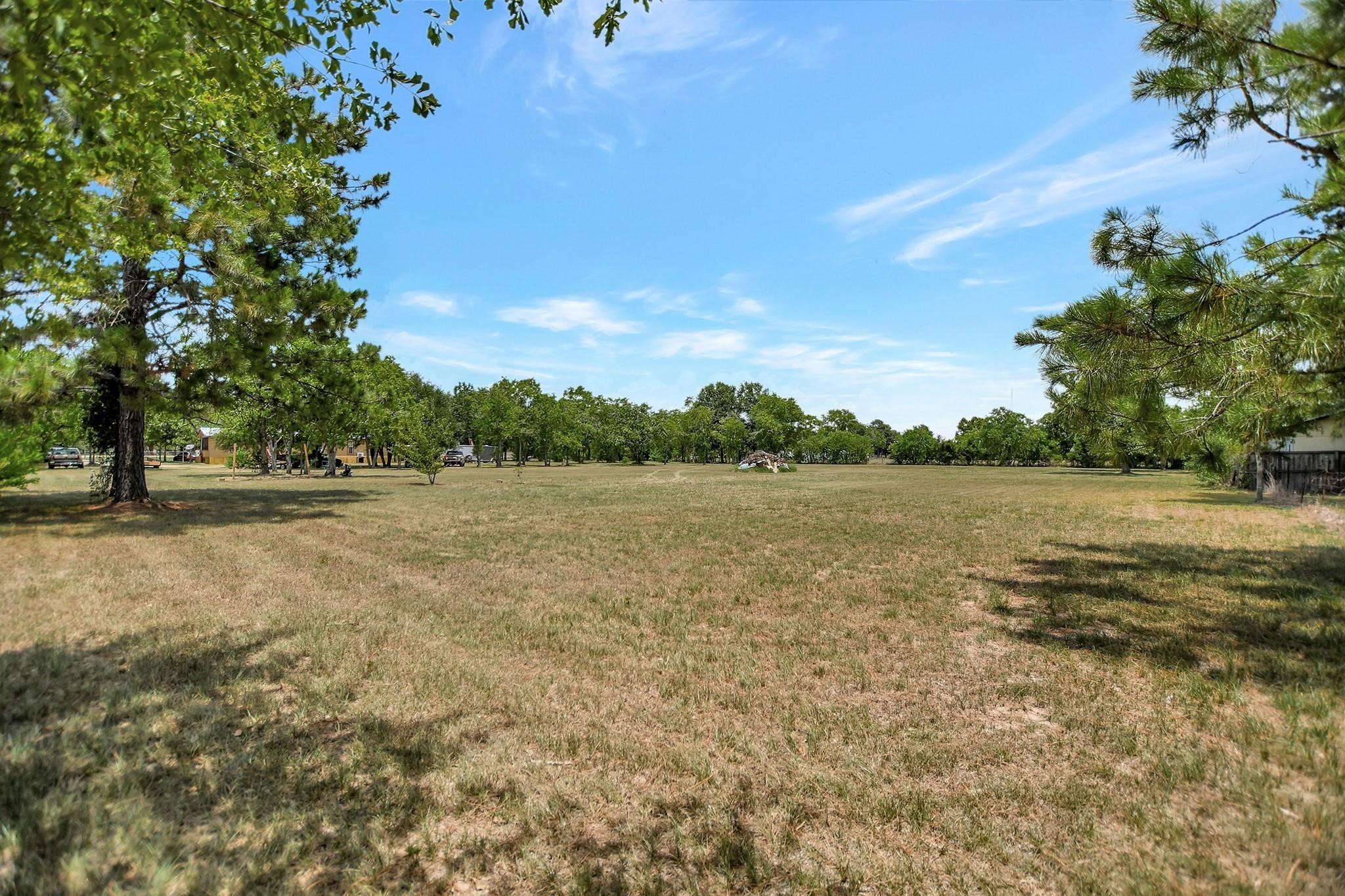 29115 Cherokee Lane Waller, TX 77484 - Photo 39 of 50 Expansive grassy lot with scattered trees, offering a serene setting and ample space for development. Perfect for a custom home build with a peaceful, natural backdrop.