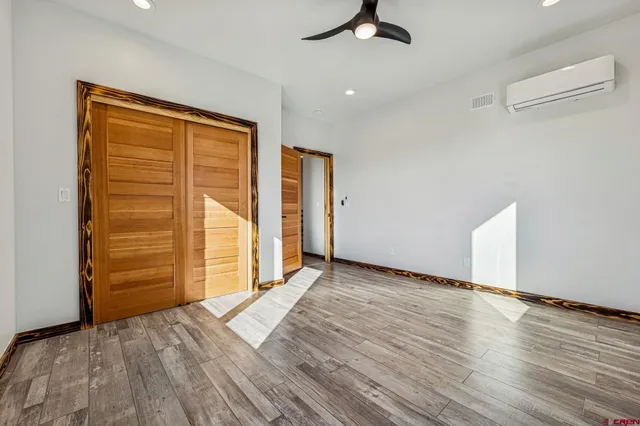 an empty room with wooden floor closet and windows