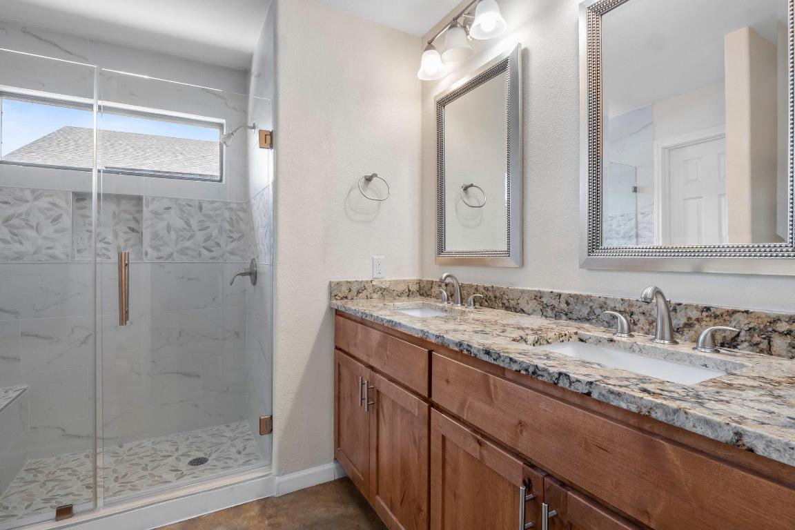 10213 Thomas Lane Dripping Springs, TX 78620 - Photo 17 of 40 a bathroom with a granite countertop sink a mirror and shower