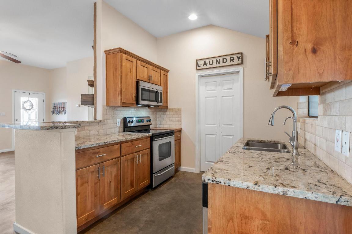 10213 Thomas Lane Dripping Springs, TX 78620 - Photo 10 of 40 a kitchen with stainless steel appliances granite countertop a sink stove and cabinets