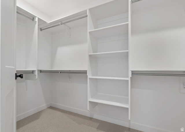 11214 South Easy Bee Road, Unit 270 South Jordan, UT 84009 - Photo 24 of 31 Walk-in closet featuring built-in shelving, multiple hanging rods, white trim, and light-toned carpeting