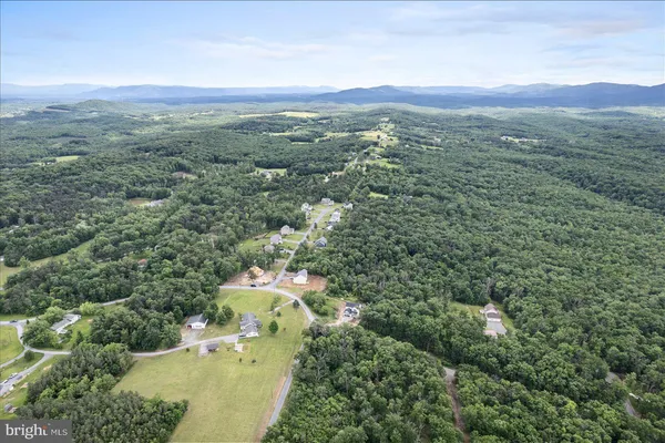 an aerial view of a houses with a yard and mountain