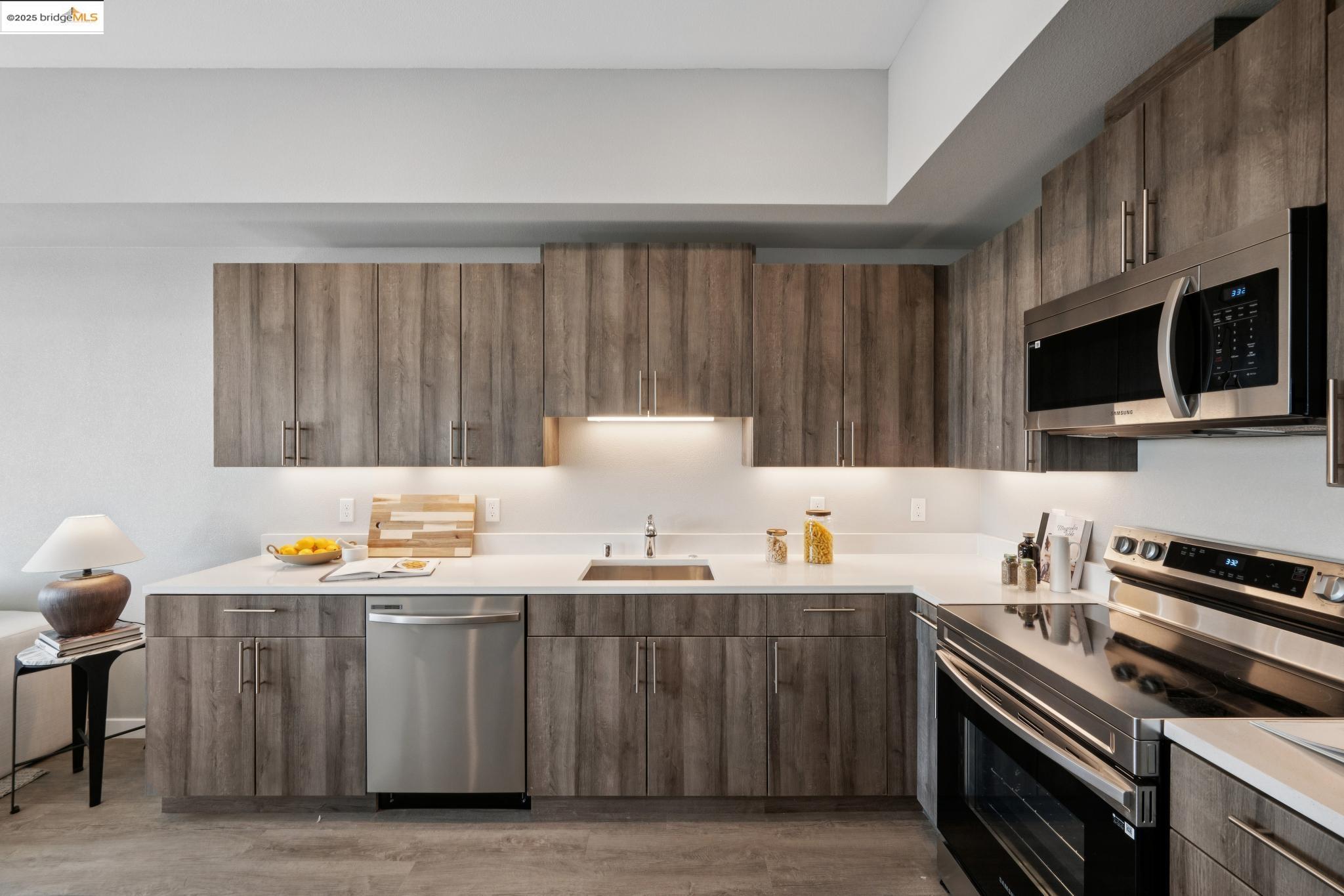 2400 Adeline Street, Unit 403 Oakland, CA 94607 - Photo 10 of 25 a kitchen with stainless steel appliances a stove a sink a microwave a refrigerator and cabinets