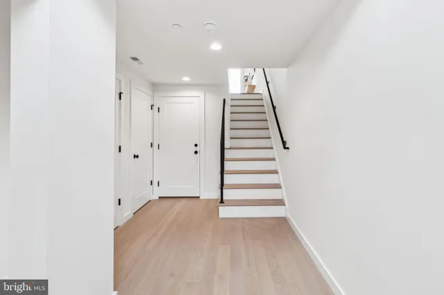 a kitchen with stainless steel appliances granite countertop a refrigerator a sink dishwasher a stove and a dining table with wooden floor