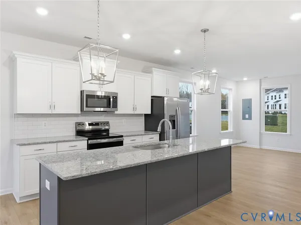 a kitchen with stainless steel appliances kitchen island granite countertop a sink a stove and cabinets