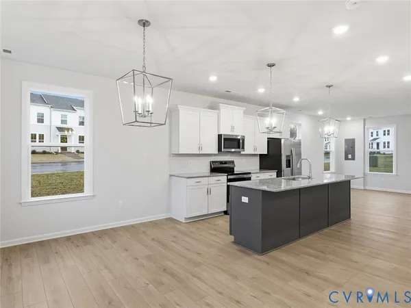 a large kitchen with kitchen island a large counter top and stainless steel appliances