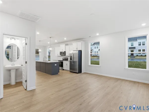 a large white kitchen with stainless steel appliances kitchen island a large counter top and a wooden floors