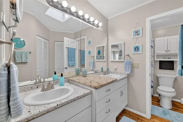 a spacious bathroom with a granite countertop double vanity sink a mirror and a toilet
