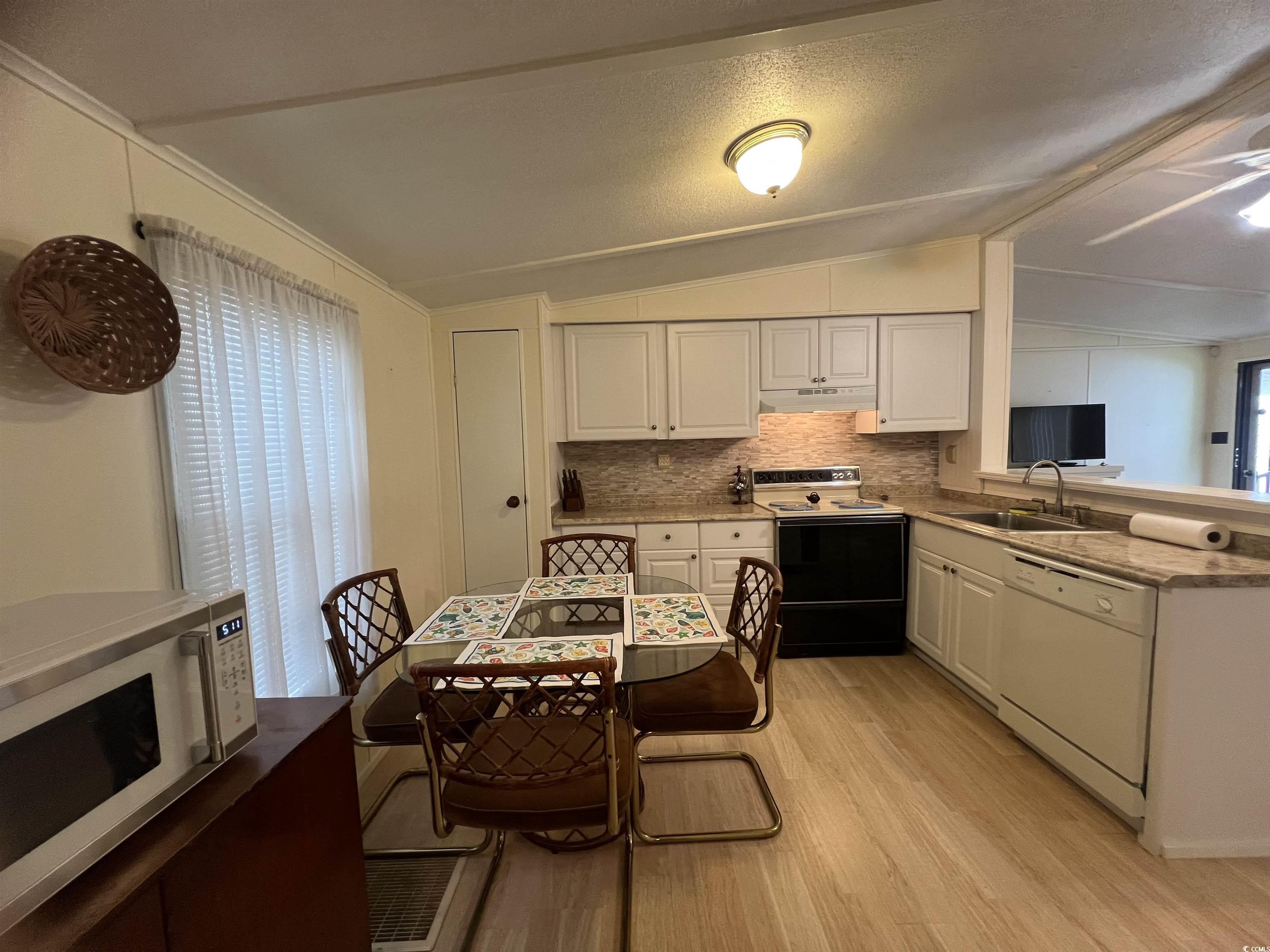 54 Crooked Island Circle Murrells Inlet, SC 29576 - Photo 21 of 37 Kitchen featuring white appliances, white cabinets, light wood finished floors, under cabinet range hood, and backsplash