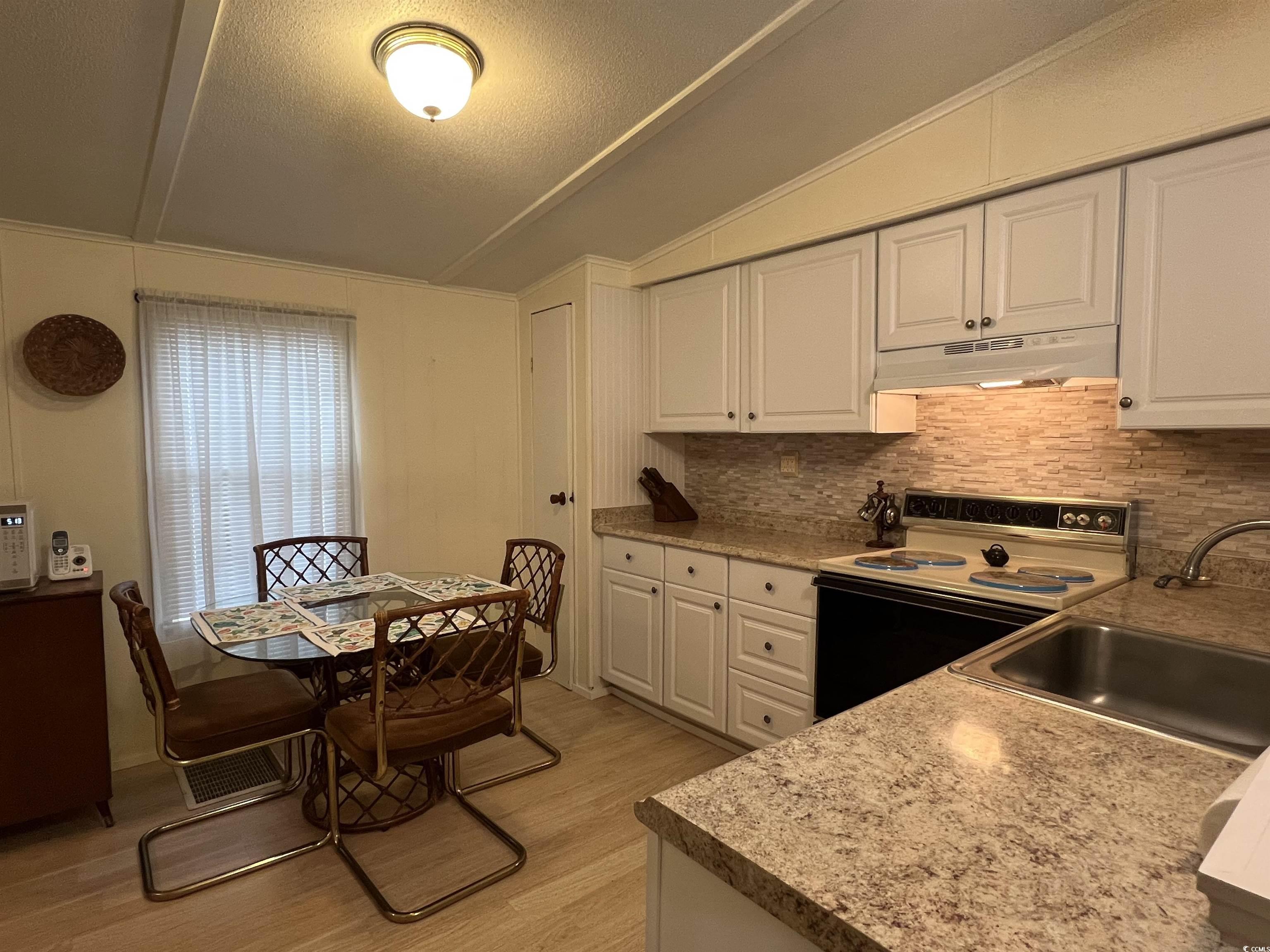 54 Crooked Island Circle Murrells Inlet, SC 29576 - Photo 29 of 37 Kitchen featuring white cabinetry, white electric stove, light wood-style floors, lofted ceiling, and light countertops