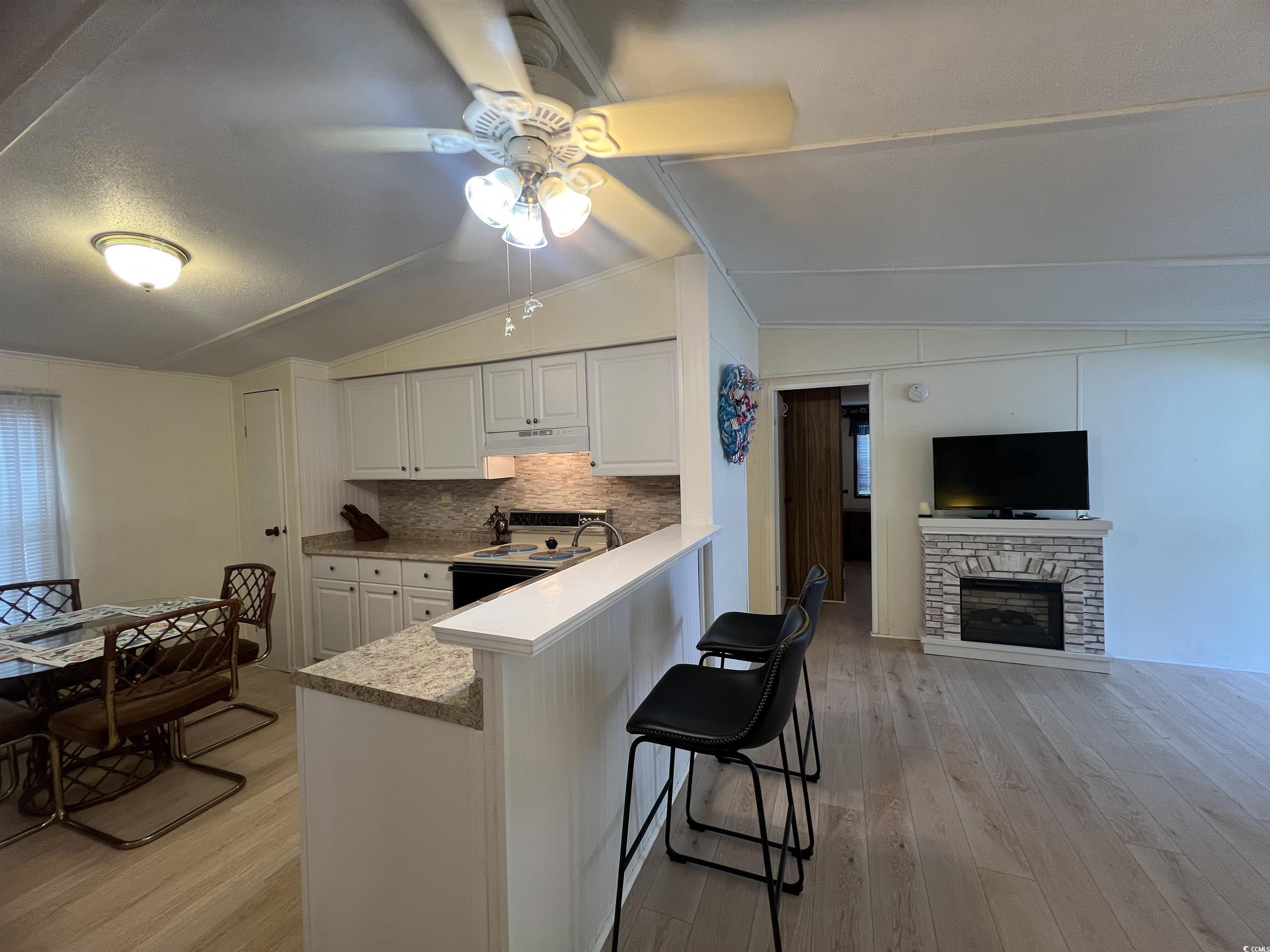 54 Crooked Island Circle Murrells Inlet, SC 29576 - Photo 7 of 37 Kitchen featuring vaulted ceiling, light wood-type flooring, backsplash, white cabinetry, and ceiling fan