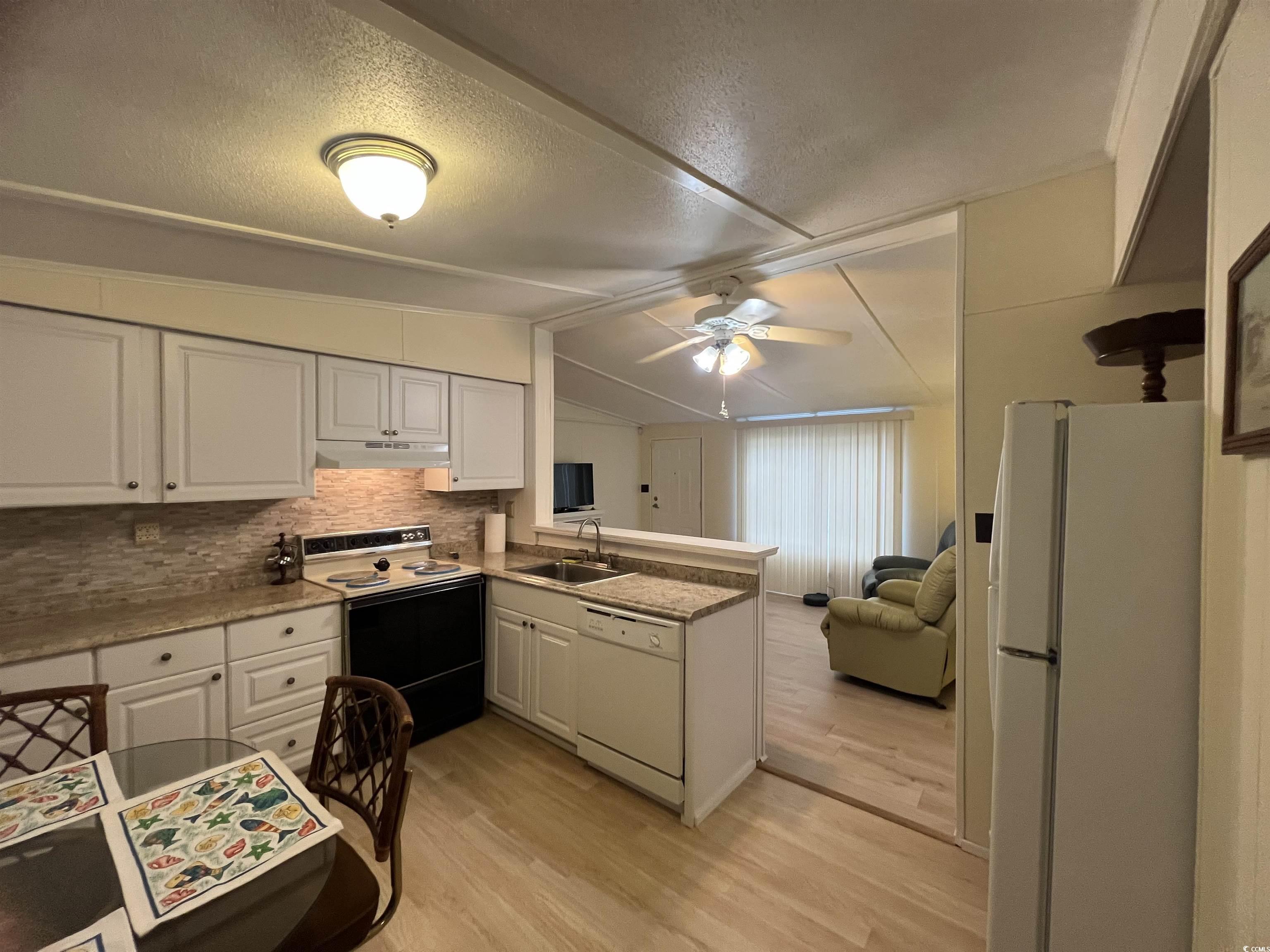 54 Crooked Island Circle Murrells Inlet, SC 29576 - Photo 36 of 37 Kitchen with white appliances, light wood-style floors, open floor plan, decorative backsplash, and white cabinets