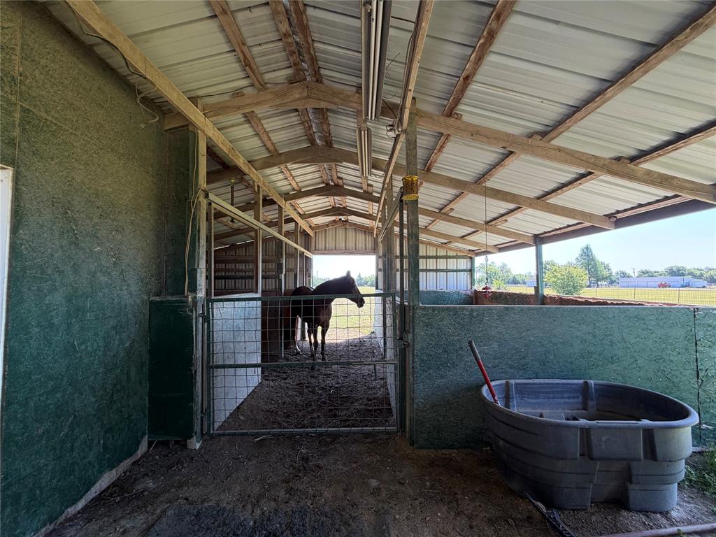 330 South Goode Road Wilmer, TX 75172 - Photo 34 of 37 Metal roof barn structure with exposed wood beams and enclosed stalls featuring metal gates